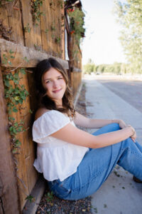 senior portrait posed against a rustic fence with vines