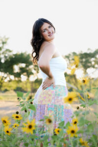 What to wear for senior pictures: senior girl in a white tank top and patchwork maxi skirt in a sunflower field